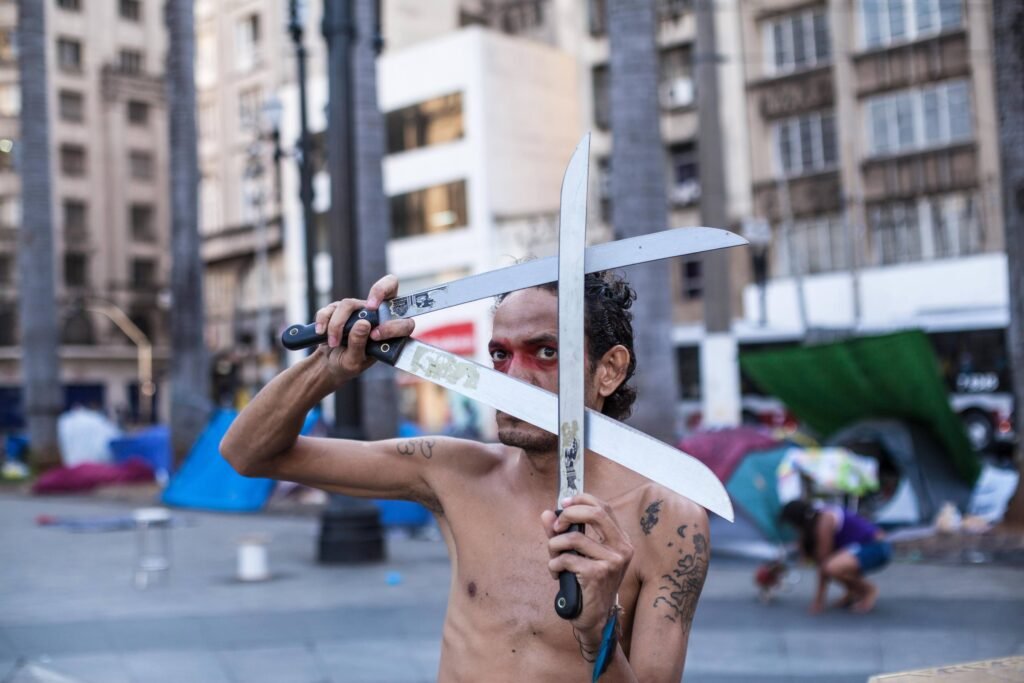 Ismael Trabuco cruza dois facões diante do rosto, na Praça da Sé