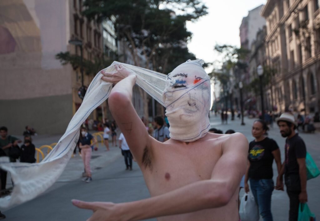 Reyan Perovano estica o tecido branco que envolve sua cabeça, no Anhangabaú