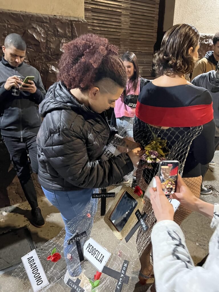 Uma mulher se inclina sobre a rede presa ao corpo de Cassia Pires, enquanto outra pessoa fotografa com o celular