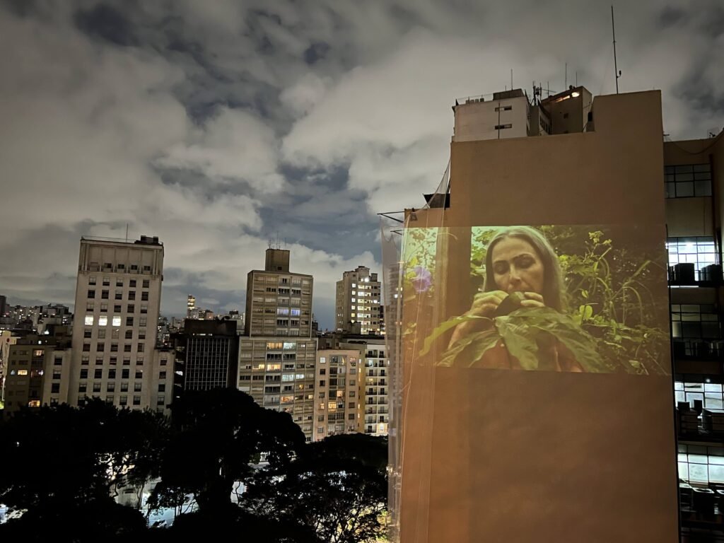 Videoperformance projetada na empena de um prédio vizinho ao Esponja, na noite de encerramento: mulher entre folhagens