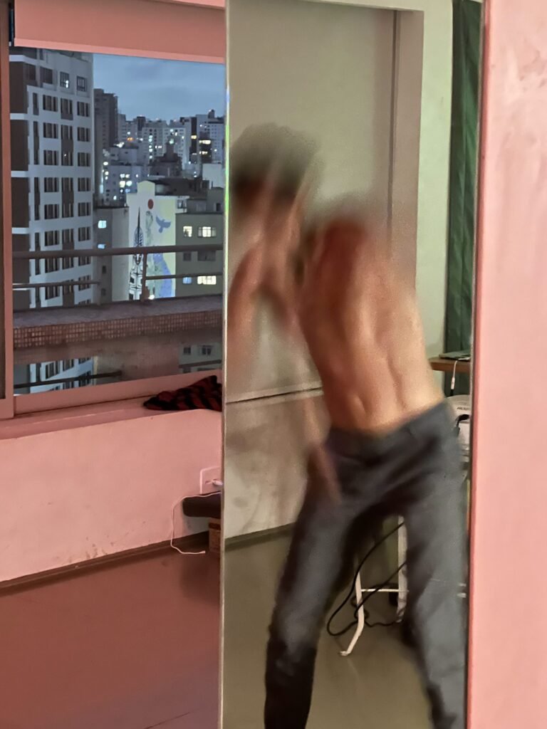 Ismael Trabuco em movimento, desfocado, refletido num espelho junto à janela
