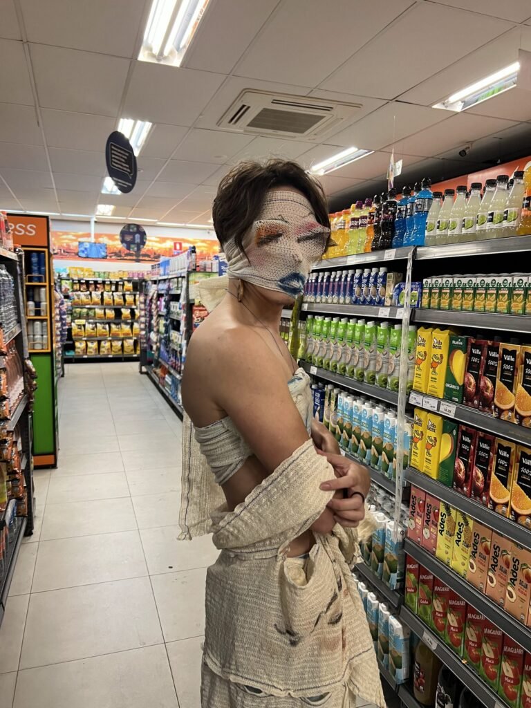 Reyan Perovano, com a máscara de atadura pintada, entre as prateleiras de um supermercado