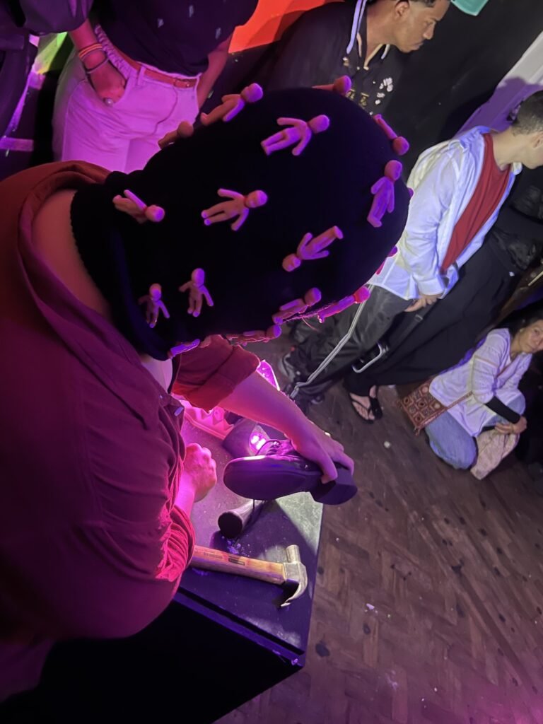 Integrante da Boleia Coletiva de balaclava bordada com figuras rosa trabalha numa sola