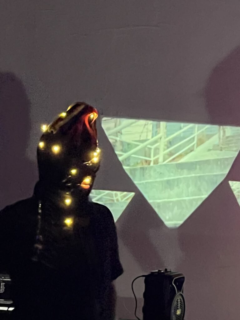 Integrante da Boleia Coletiva com luzes na cabeça diante de uma projeção