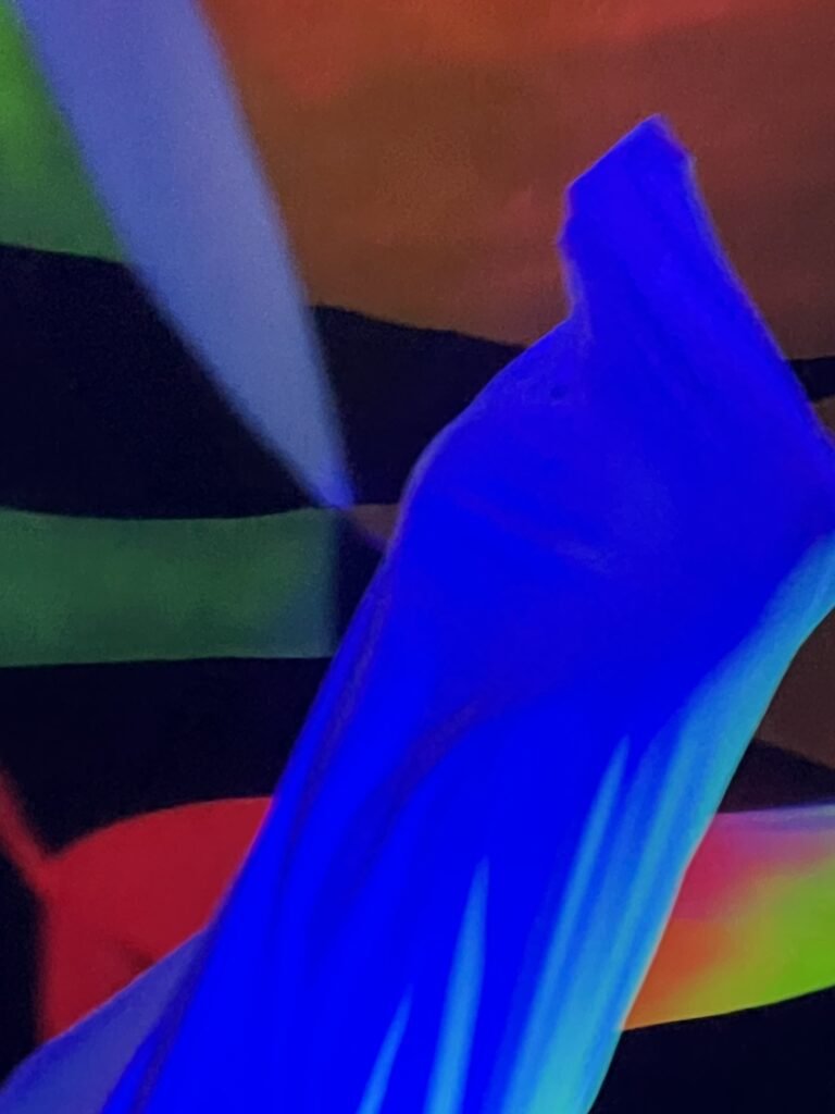 Detalhe da malha azul esticada da escultura vestível diante do mural colorido
