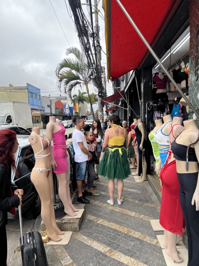 Kareen Labbé Weber caminha entre manequins e moradores numa calçada de Heliópolis