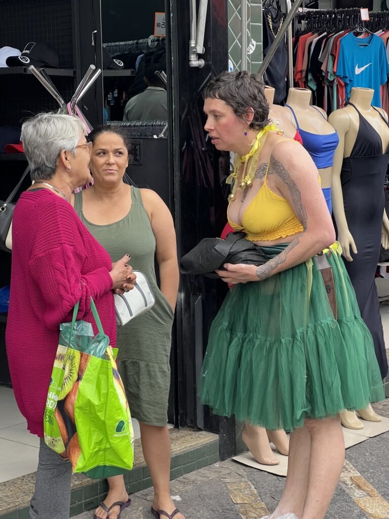 Kareen Labbé Weber conversa com duas moradoras diante de uma loja de roupas