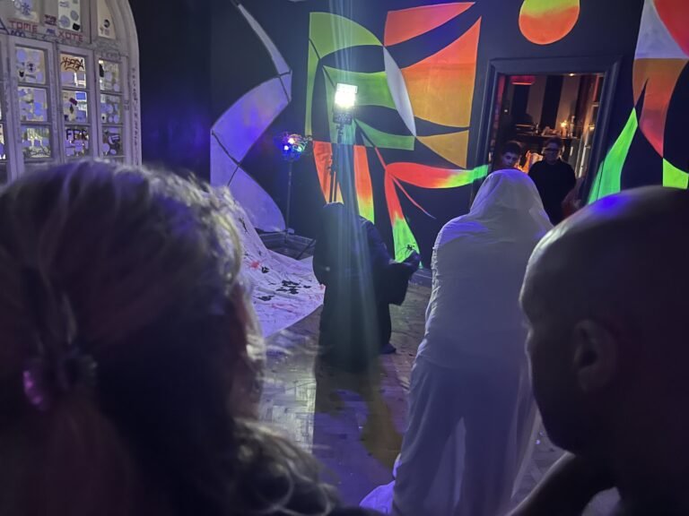 Figura coberta de chiffon branco no salão do Estúdio Lâmina, vista entre o público