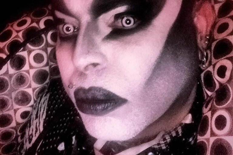Rosto de Victor Piercing em close, com maquiagem branca e preta e piercings