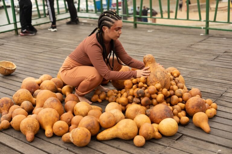 Jéssica Cruz, de tranças, agachada, arruma as cabaças no deck