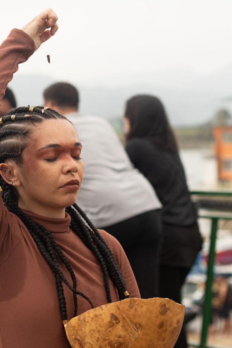 Jéssica Cruz, de olhos fechados, deixa cair sementes de uma das mãos sobre a cuia de cabaça