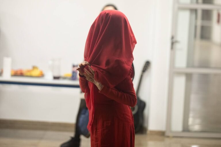 A performer cobre a cabeça e o rosto com um tecido vermelho