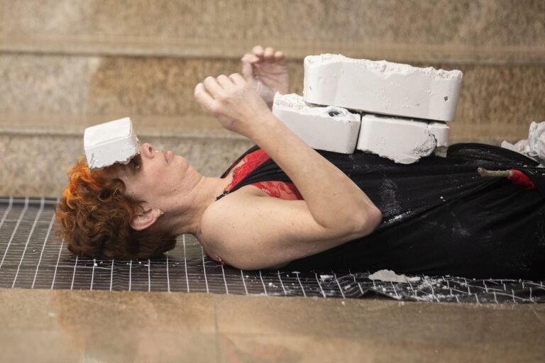 Kareen Labbé Weber deitada sobre uma tela metálica, com blocos de gesso sobre a testa e o peito