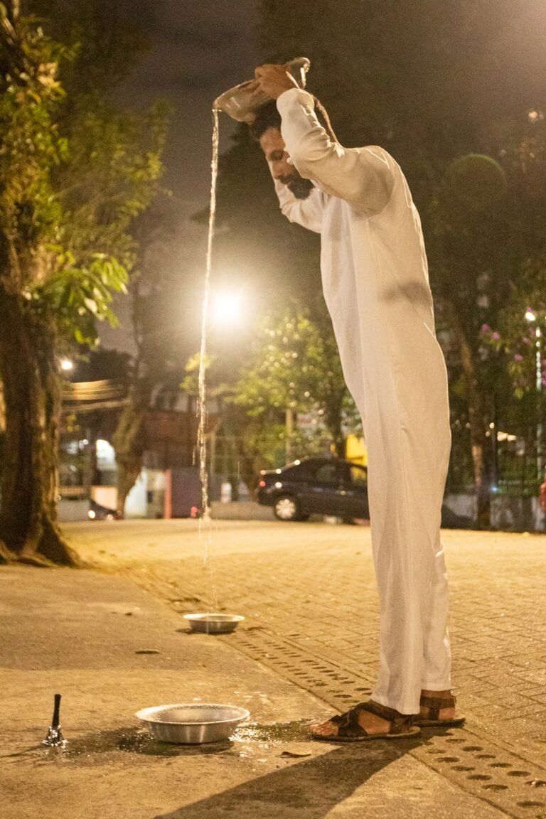 PC despeja a água de uma bacia erguida acima da cabeça sobre outra bacia aos seus pés