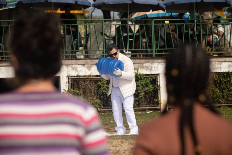 Pio Santana abraça o galão azul junto ao peito, visto entre pessoas do público