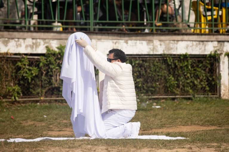 Pio Santana, ajoelhado, envolve o galão num tecido branco