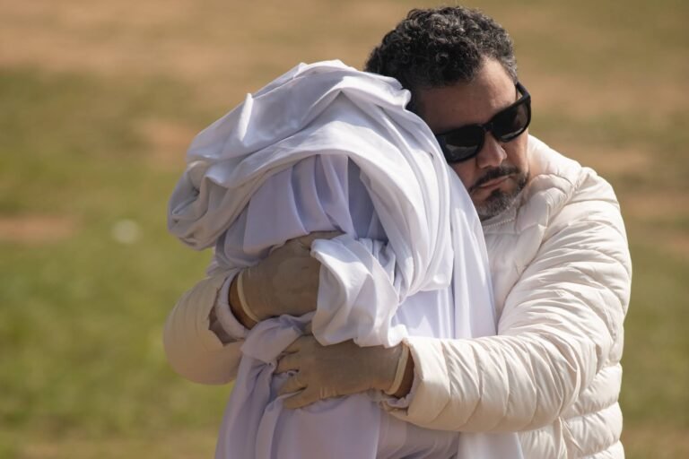 Pio Santana, de óculos escuros, abraça o volume envolto em tecido branco